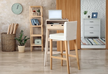 High wooden table with laptop as stand up workplace in modern interior
