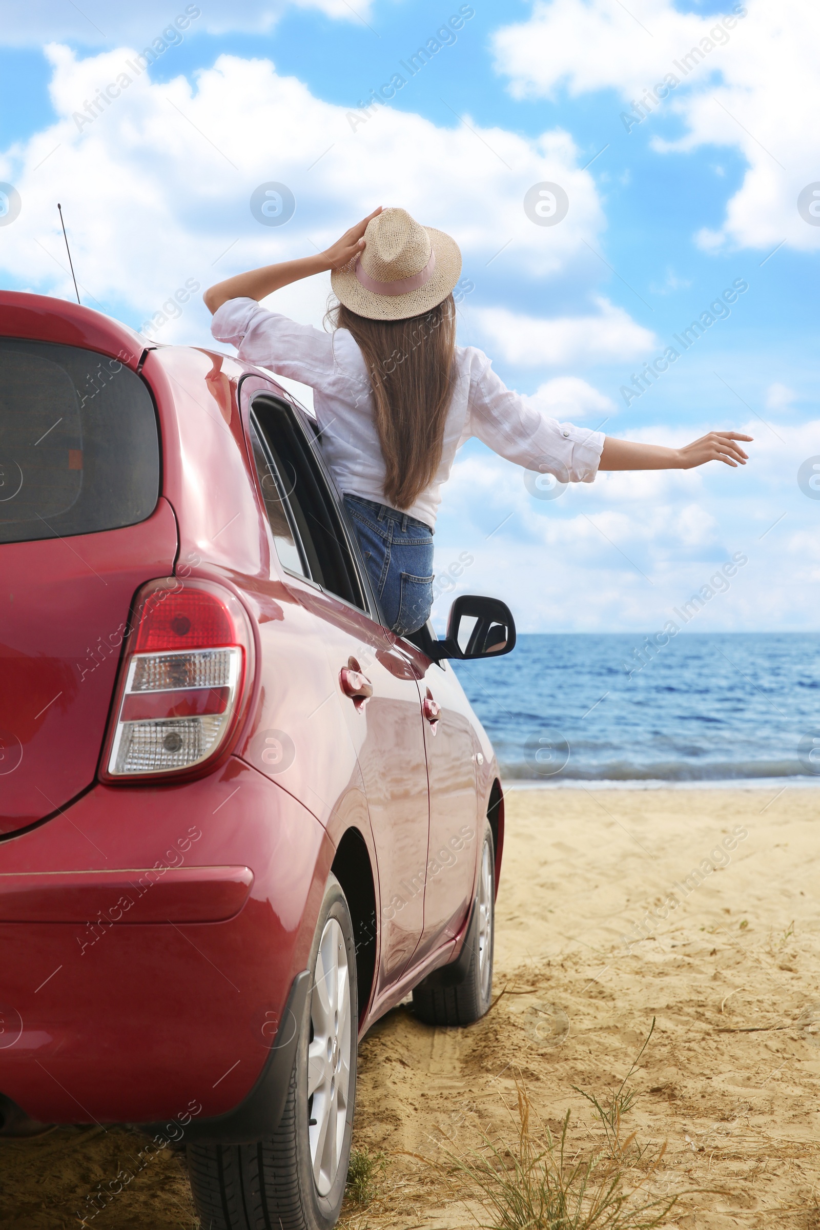 Photo of Happy woman leaning out of car window on beach. Summer vacation trip