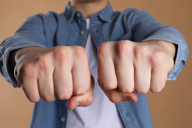 Photo of Man showing fists with space for tattoo on beige background, selective focus