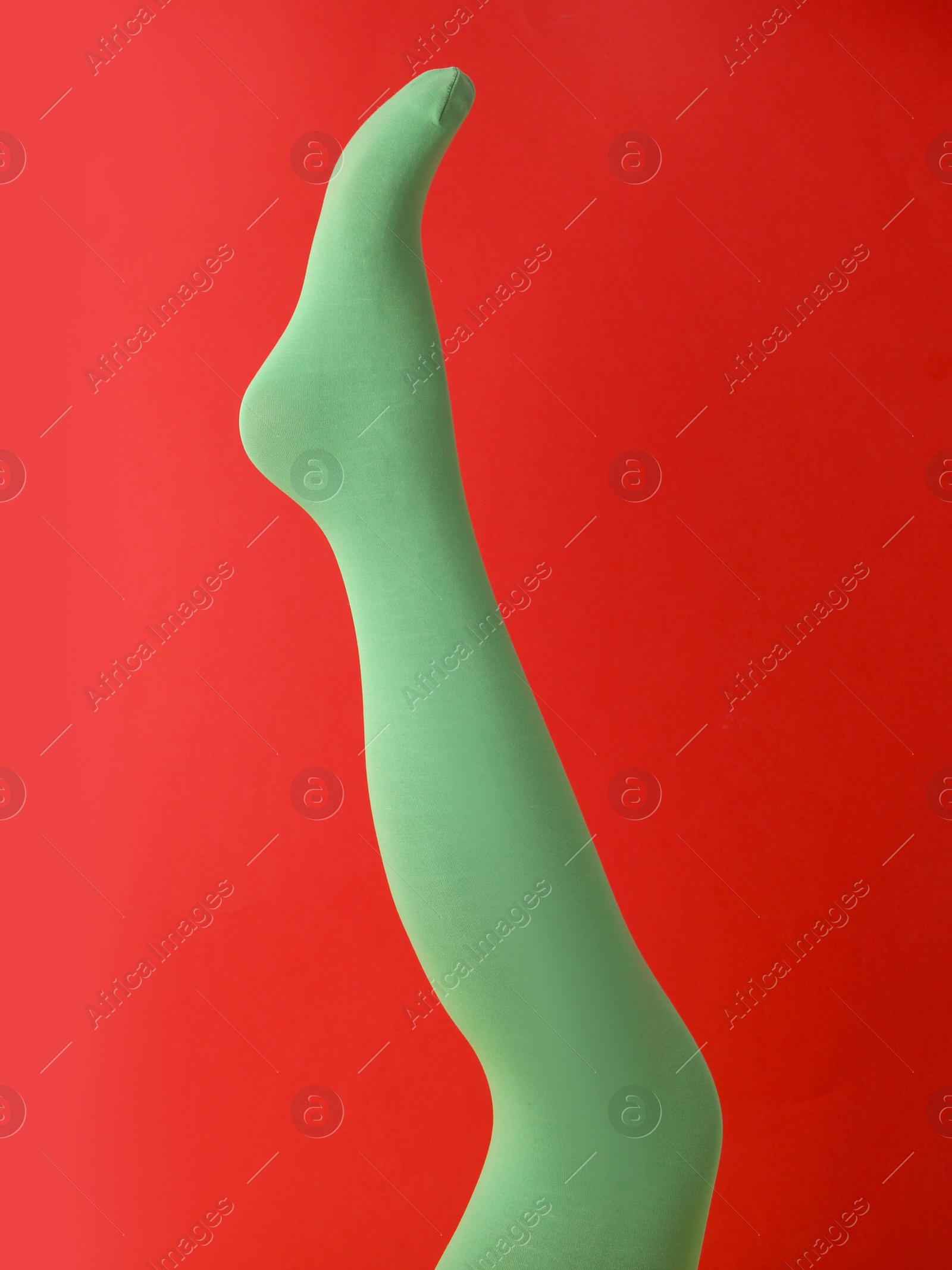 Photo of Leg mannequin in green tights on red background