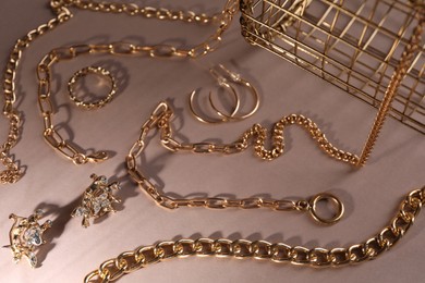Photo of Metal chains and other different accessories on light brown background, above view. Luxury jewelry