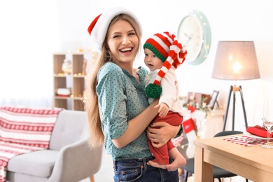 Young woman with baby in Christmas hats at home