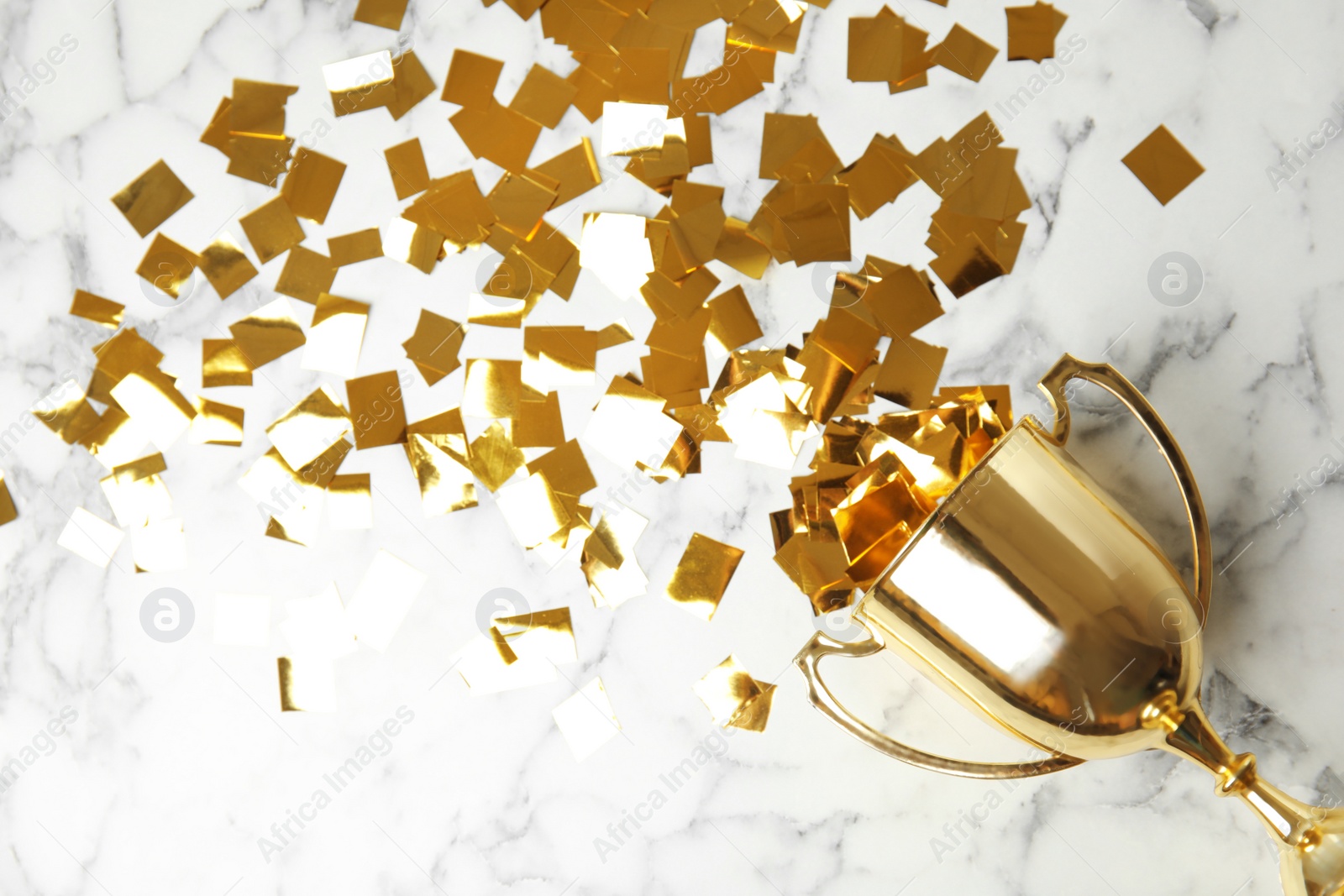 Photo of Gold trophy cup and confetti on marble background, flat lay. Space for text