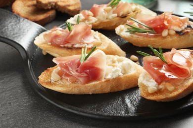 Tasty bruschettas with prosciutto and cream cheese served on table, closeup