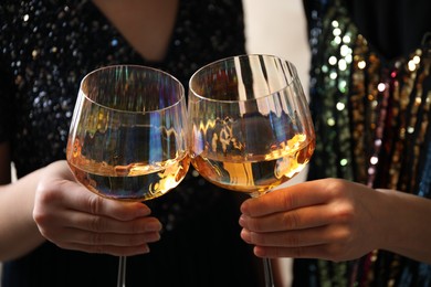 Photo of Women clinking glasses with white wine, closeup