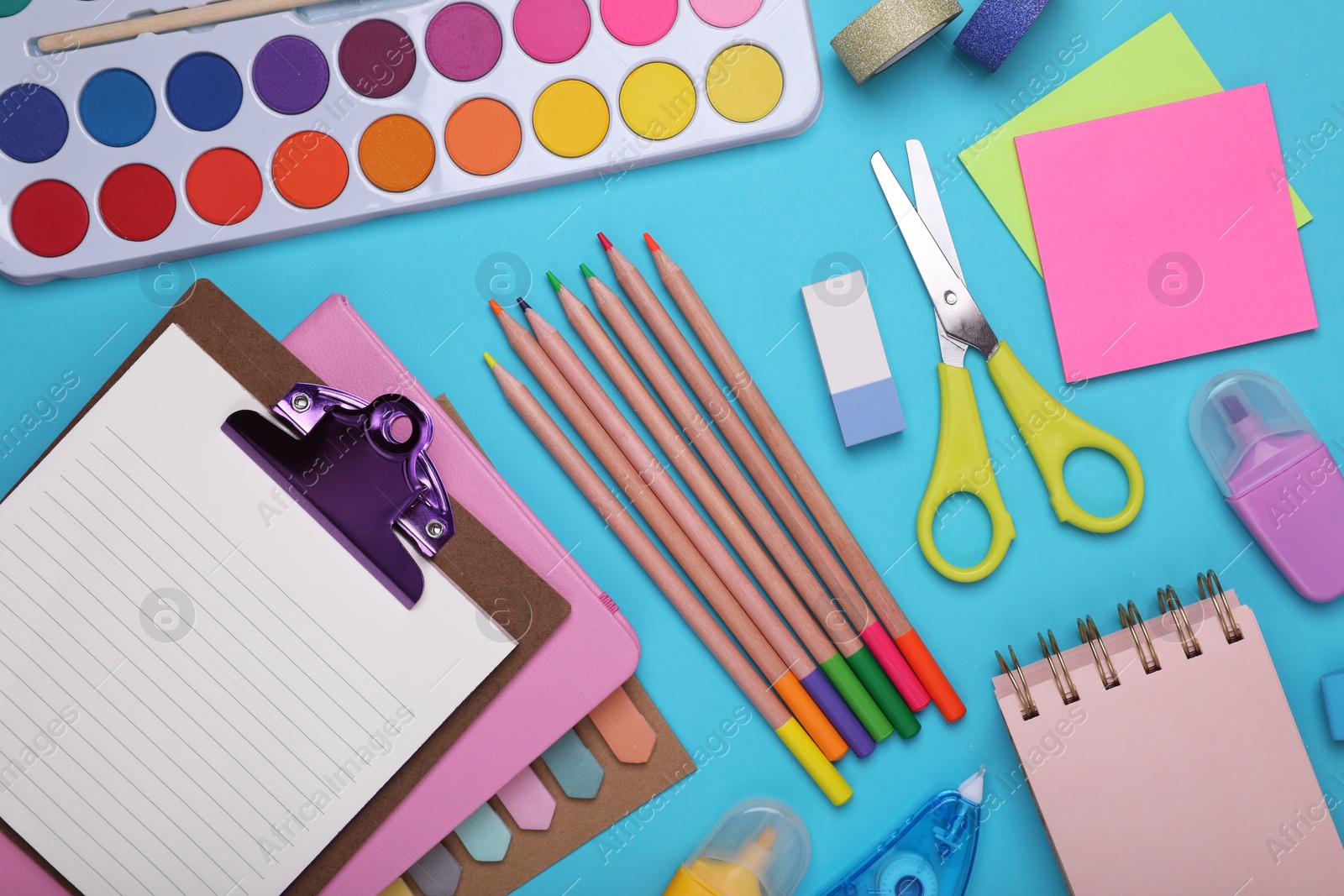 Photo of Flat lay composition with clipboard and other school stationery on light blue background. Back to school