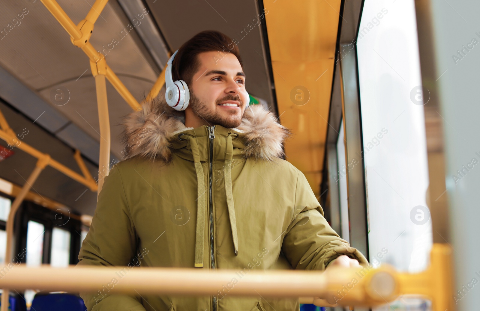 Photo of Young man listening to music with headphones in public transport