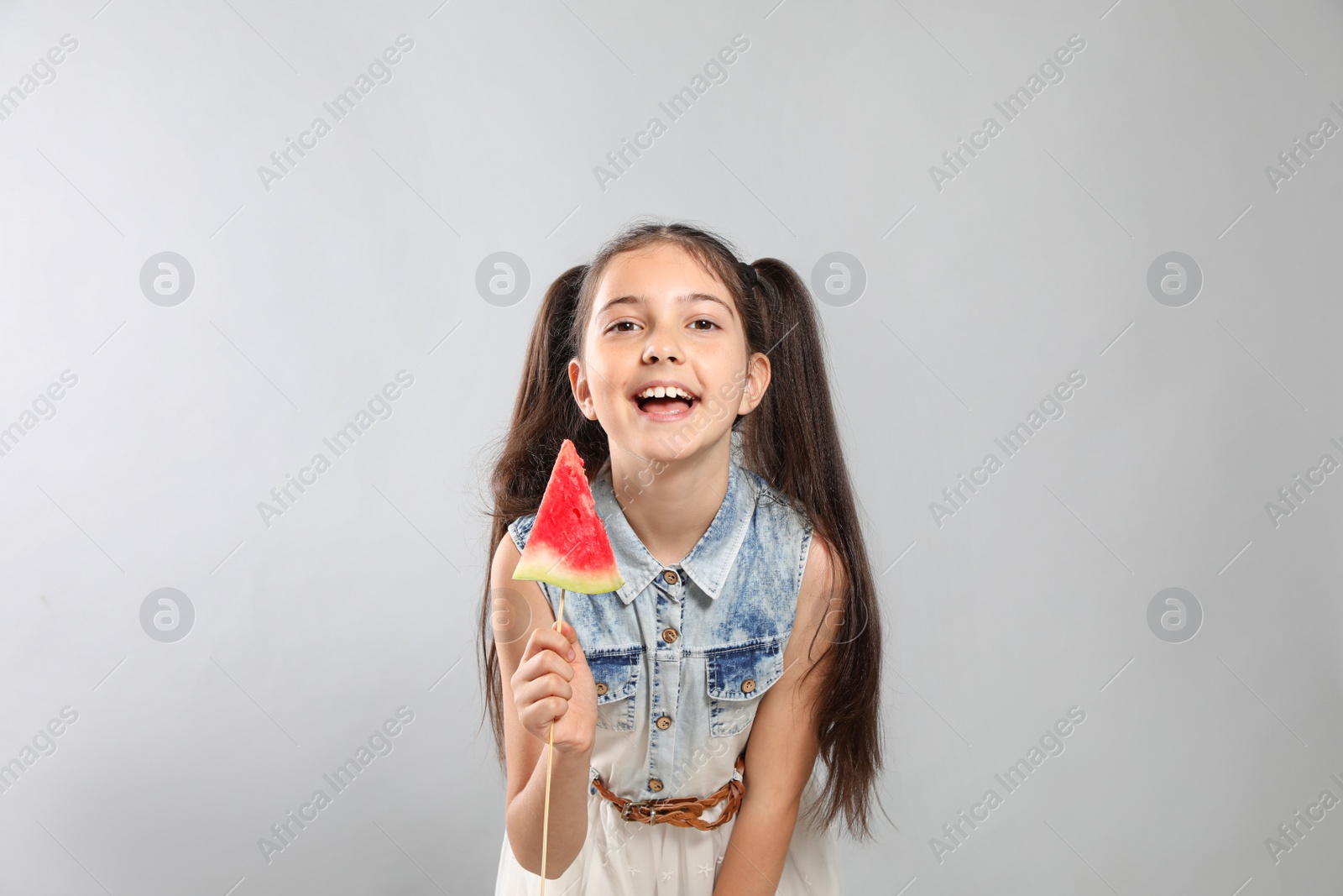 Photo of Cute little girl with watermelon on grey background