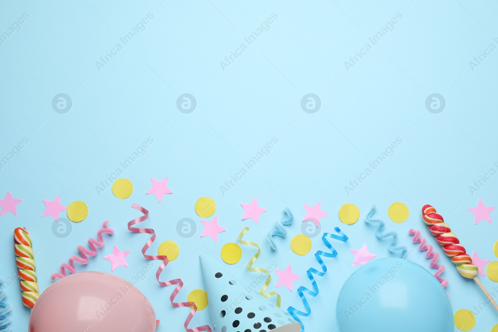 Photo of Flat lay composition with serpentine streamers and party accessories on light blue background, space for text. Birthday surprise