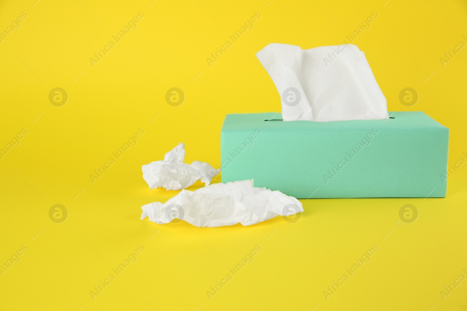 Photo of Used paper tissues and box on yellow background