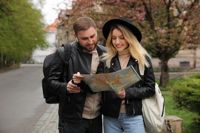 Photo of Couple of tourists with map planning trip on city street