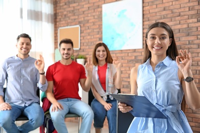 Young teacher showing sign language gesture against blurred background