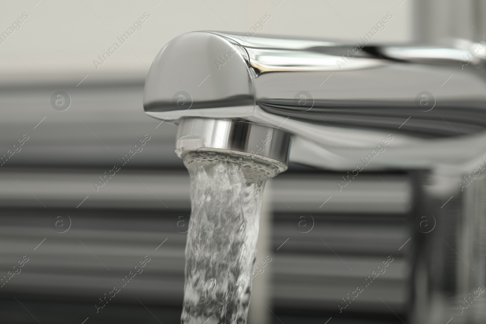 Photo of Water flowing from tap on blurred background, closeup