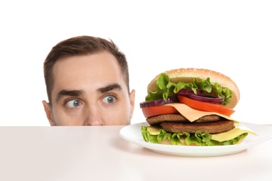Young man with tasty burger on white background
