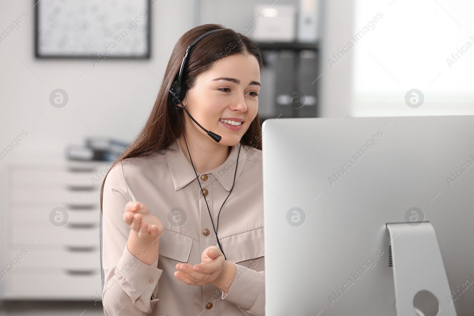 Photo of Hotline operator with headset working on computer in office