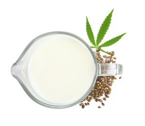 Photo of Glass jug with fresh hemp milk, seeds and leaf on white background, top view