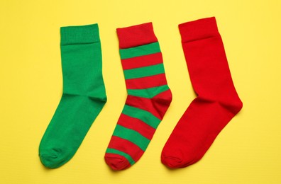 Photo of Different green and red socks on yellow background, flat lay