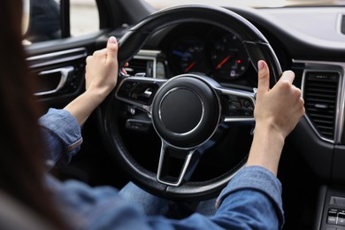 Photo of Woman holding steering wheel while driving her car, closeup