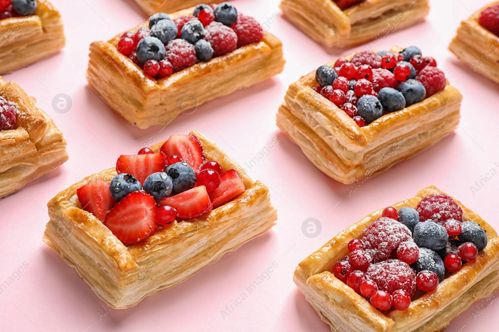 Photo of Fresh delicious puff pastry with sweet berries on pink background