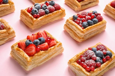 Fresh delicious puff pastry with sweet berries on pink background