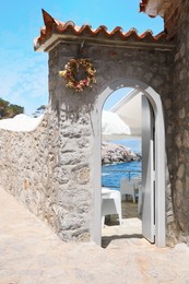 Photo of Beautiful seaside terrace with wreath near entrance on sunny day
