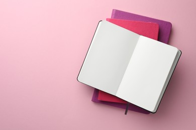 Photo of Different notebooks on light pink background, top view. Space for text