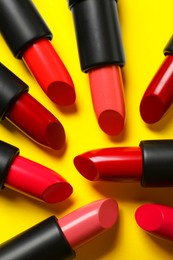 Photo of Many bright lipsticks on yellow background, flat lay