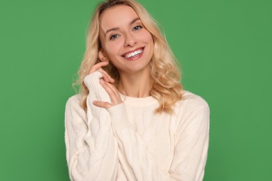 Happy woman in stylish warm sweater on green background