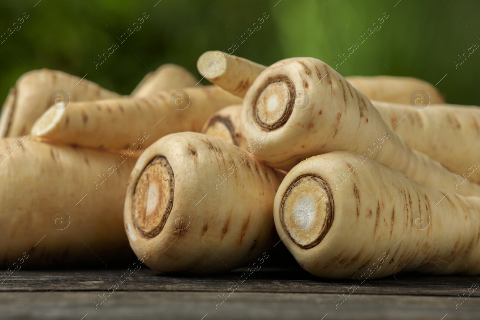 Photo of Delicious fresh ripe parsnips on wooden table outdoors, closeup