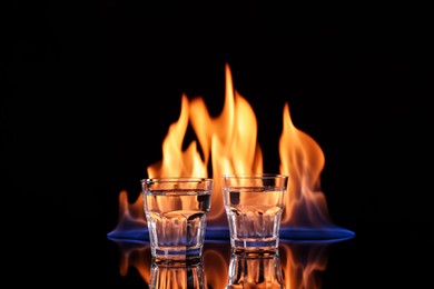 Photo of Vodka in glasses and flame on black background