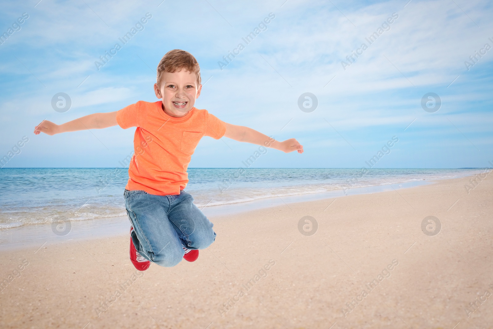 Image of Happy school boy jumping on beach near sea. Summer holidays