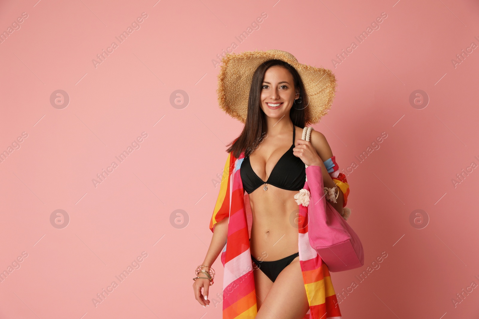 Photo of Pretty sexy woman with slim body in stylish black bikini on coral background, space for text