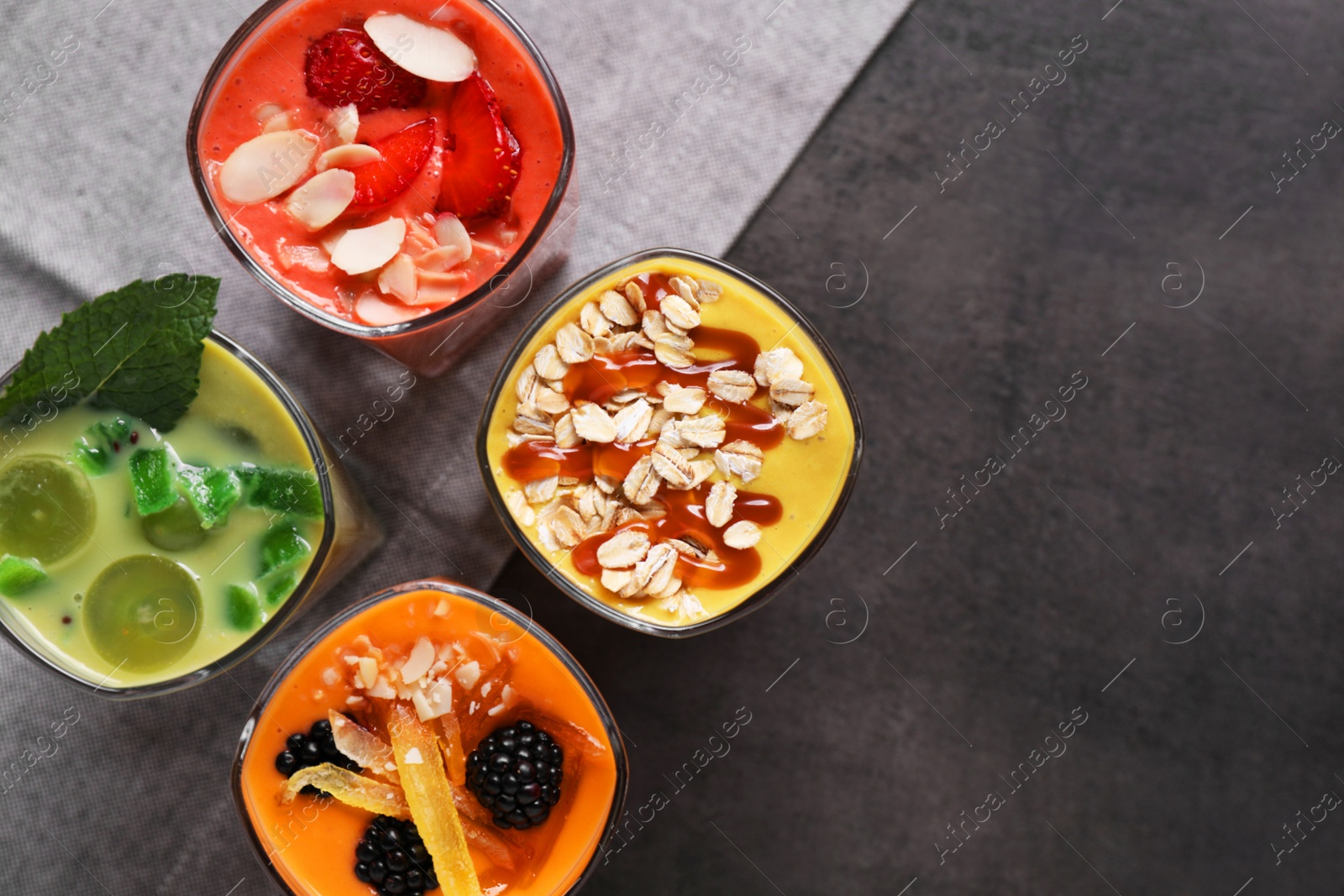 Photo of Many different delicious smoothies on grey table, flat lay. Space for text