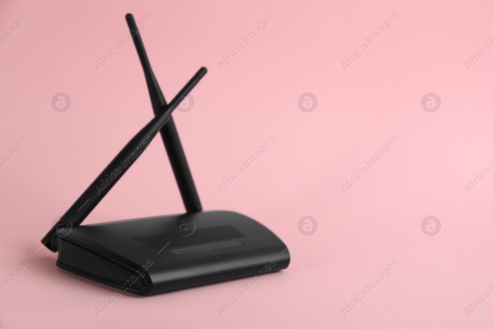 Photo of Modern Wi-Fi router on light pink background. Space for text
