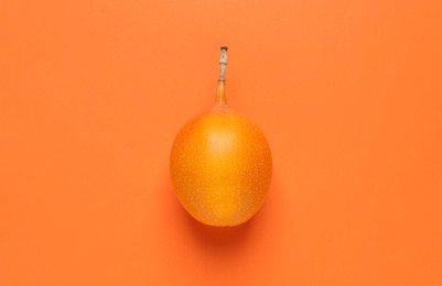 Photo of Delicious ripe granadilla on orange background, top view