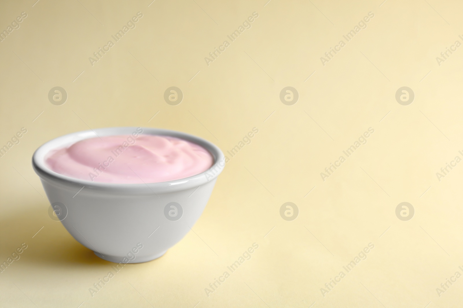 Photo of Bowl with tasty yogurt on color background