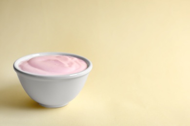 Photo of Bowl with tasty yogurt on color background