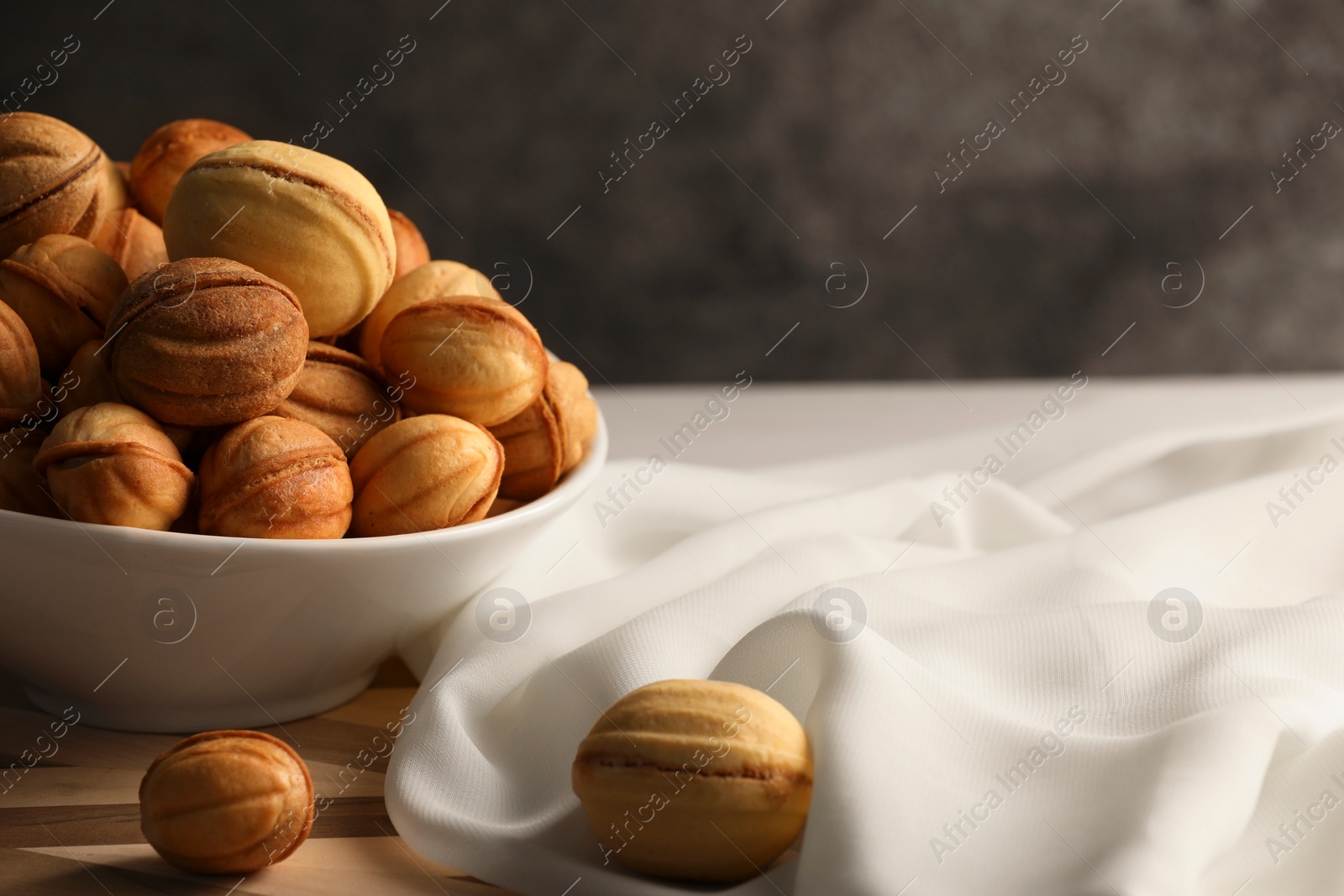 Photo of Freshly baked walnut shaped cookies on wooden board, space for text. Homemade pastry filled with caramelized condensed milk