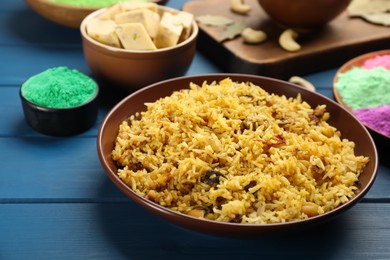 Traditional Indian food and color powders on blue wooden table. Holi festival celebration