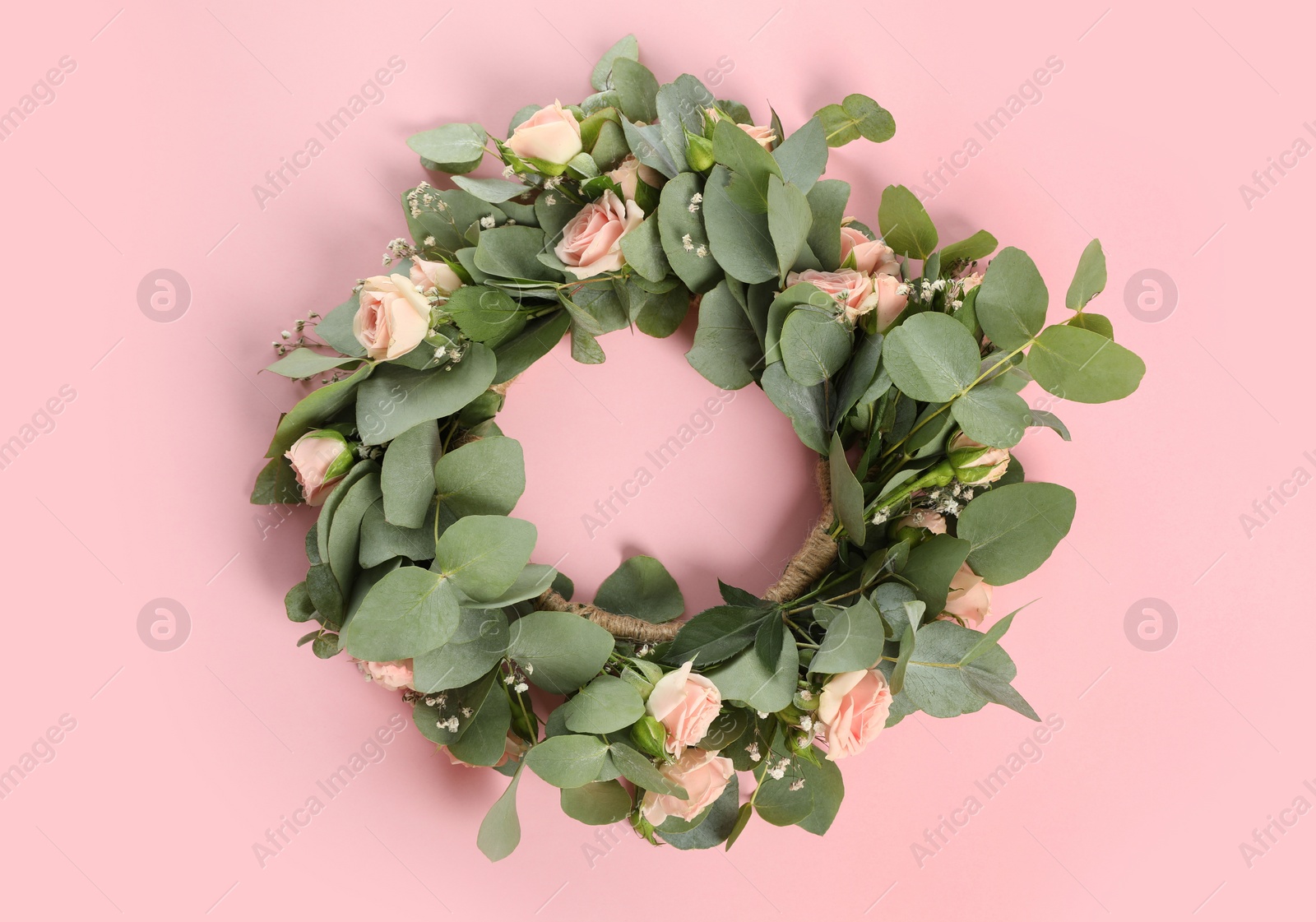 Photo of Wreath made of beautiful flowers on pink background, top view
