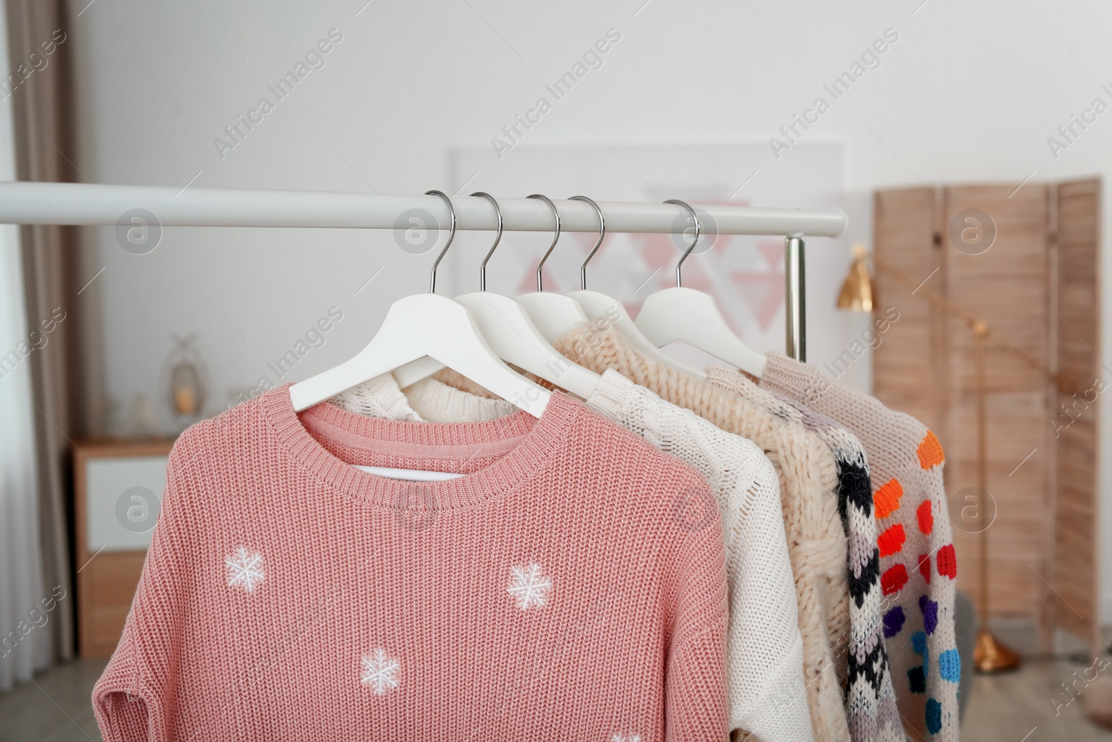 Photo of Wardrobe rack with warm clothes indoors, closeup