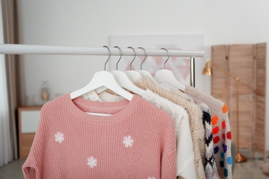 Photo of Wardrobe rack with warm clothes indoors, closeup