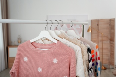 Wardrobe rack with warm clothes indoors, closeup