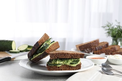 Tasty sandwiches with cucumber, cream cheese and dill on grey table indoors