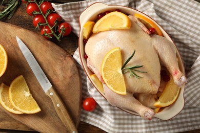 Photo of Chicken with orange slices and other ingredients on wooden table, flat lay