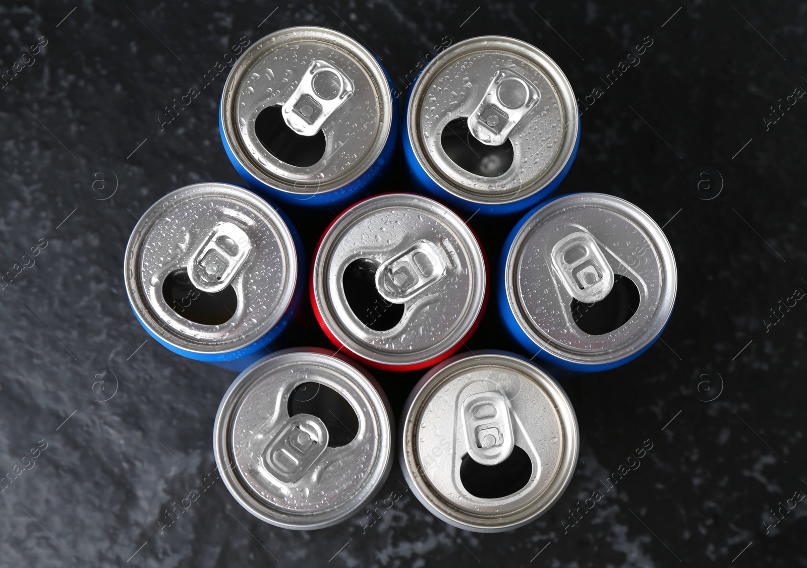 Photo of Energy drinks in wet cans on black textured table, flat lay. Functional beverage