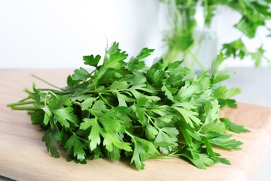 Photo of Wooden board with fresh green parsley on table