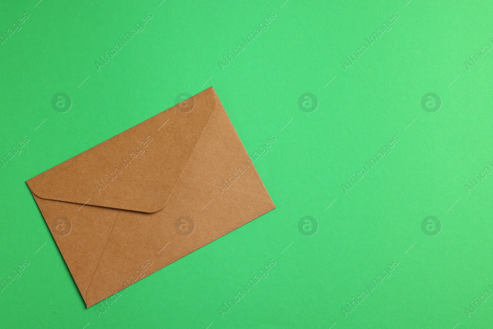 Photo of Envelope made of parchment paper on green background, top view. Space for text