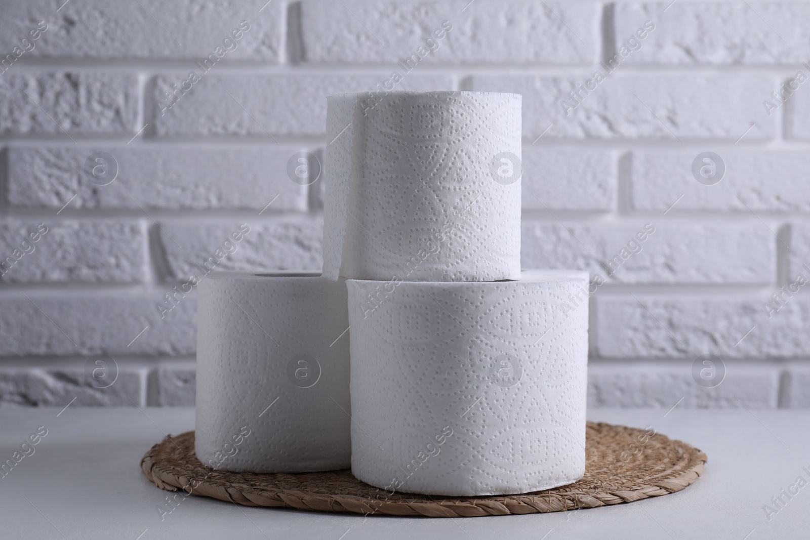 Photo of Toilet paper rolls on white table against brick wall
