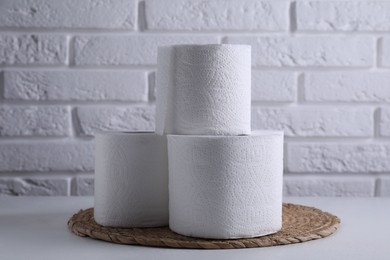 Toilet paper rolls on white table against brick wall